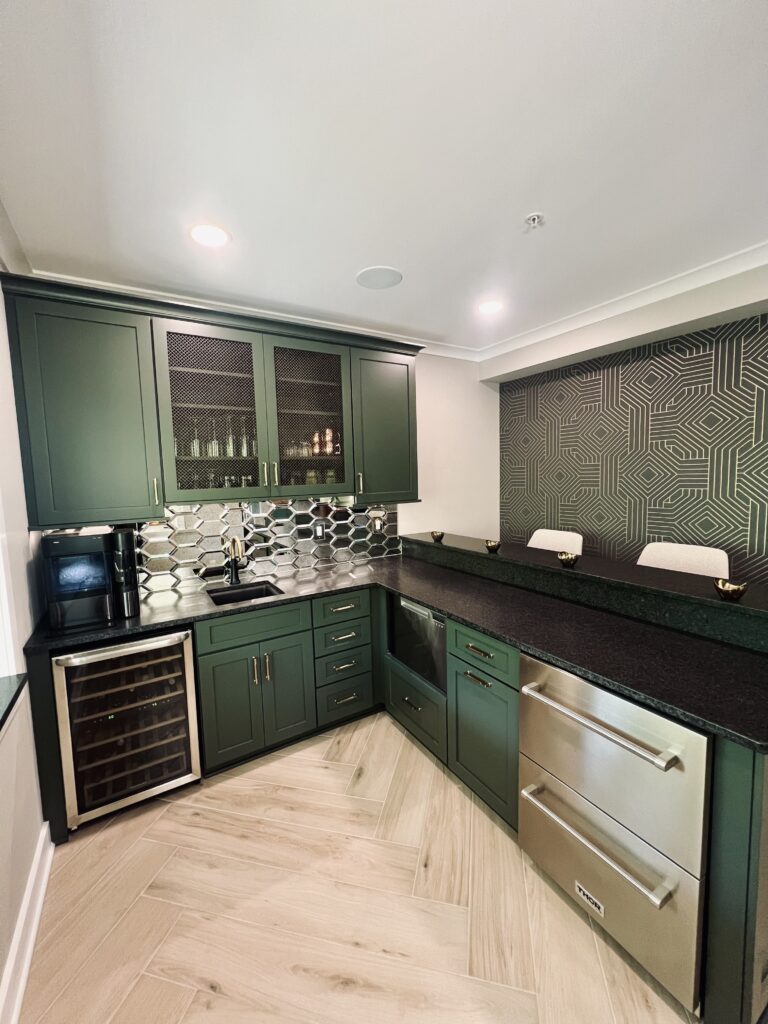 basement bar with green cabinets, black counters, and mirrored backsplash